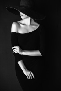 Studio shot of young beautiful woman wearing hat on dark background